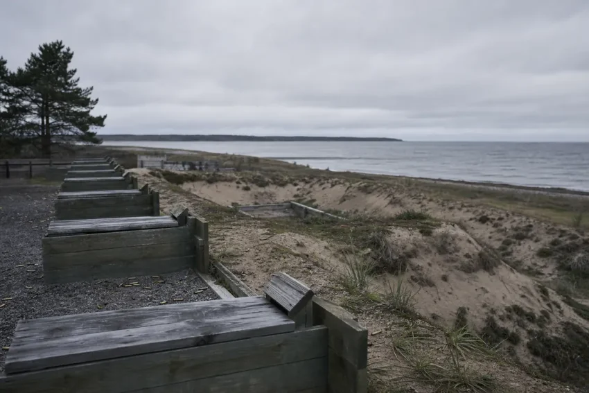 Tom skjutbana vid en kust i grått dagsljus med väderbitna skjutplatser och grus